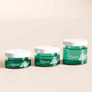 Three green cylindrical cosmetic jars (100ml, 150ml, 250ml) with white caps are arranged in size order on a light surface.