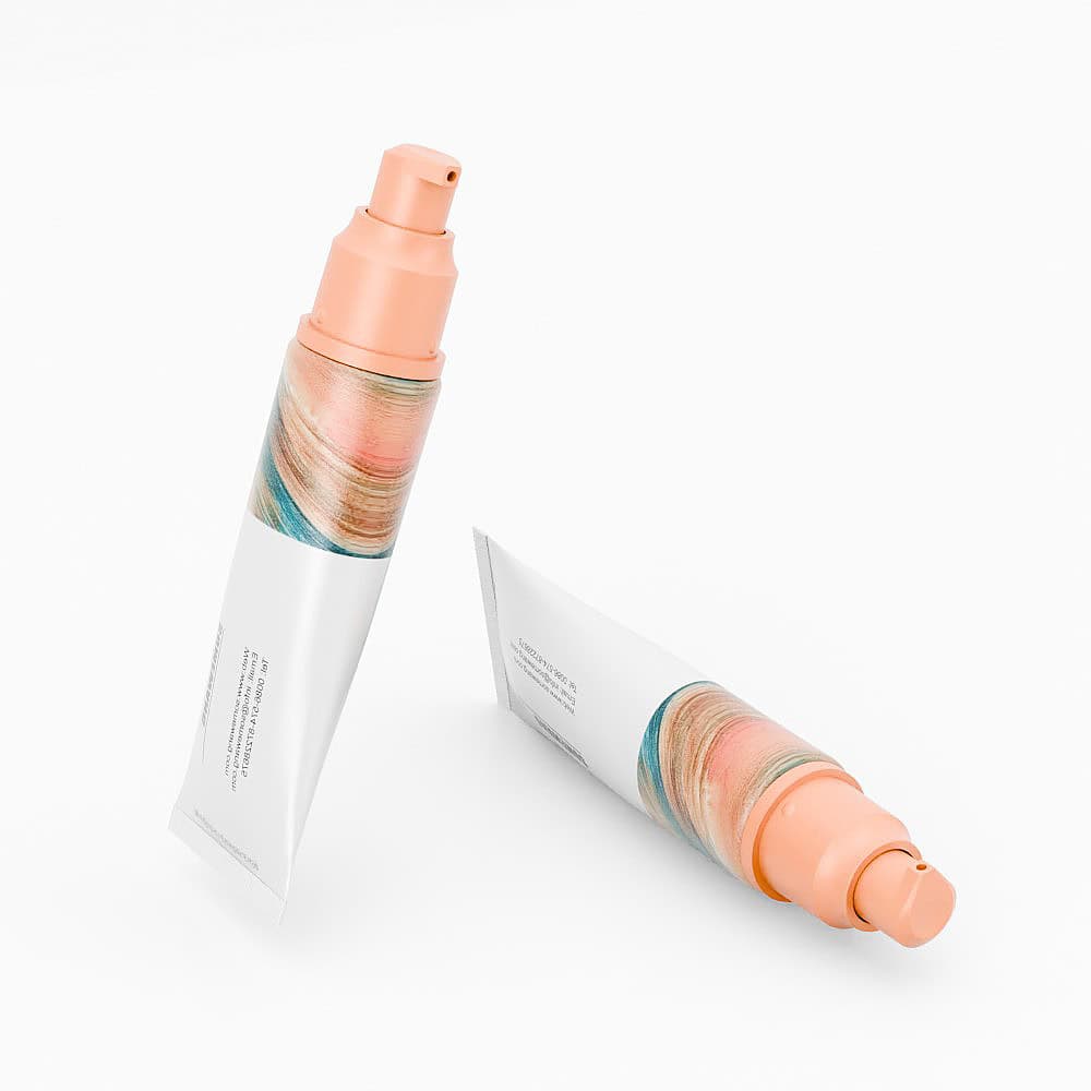 Two wheat straw cosmetic tubes with peach caps and abstract designs are displayed upright and lying down on white backgrounds.